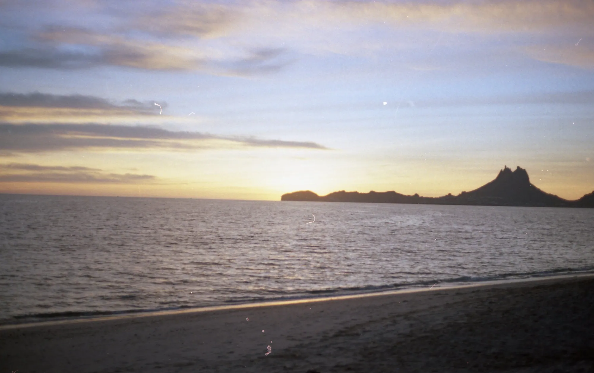 A dark coastline extending into sunset.