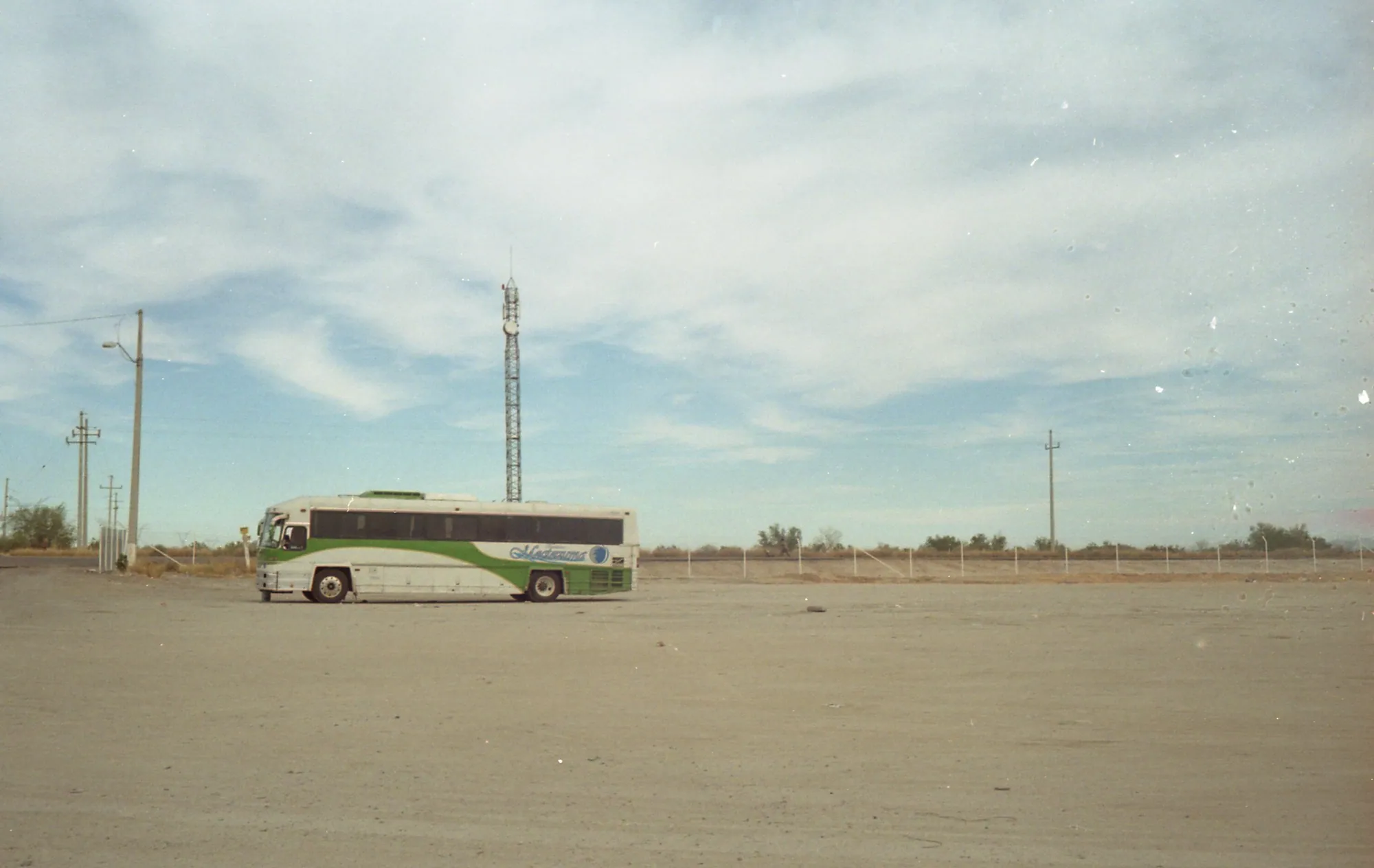 A solitary bus in a wide desert lot.