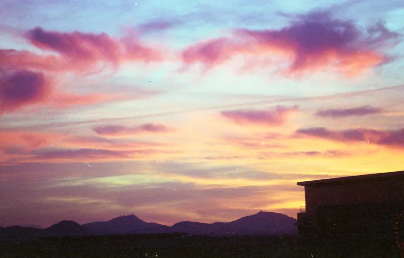 Layered mountain silhouettes beneath a pink and violet evening sky